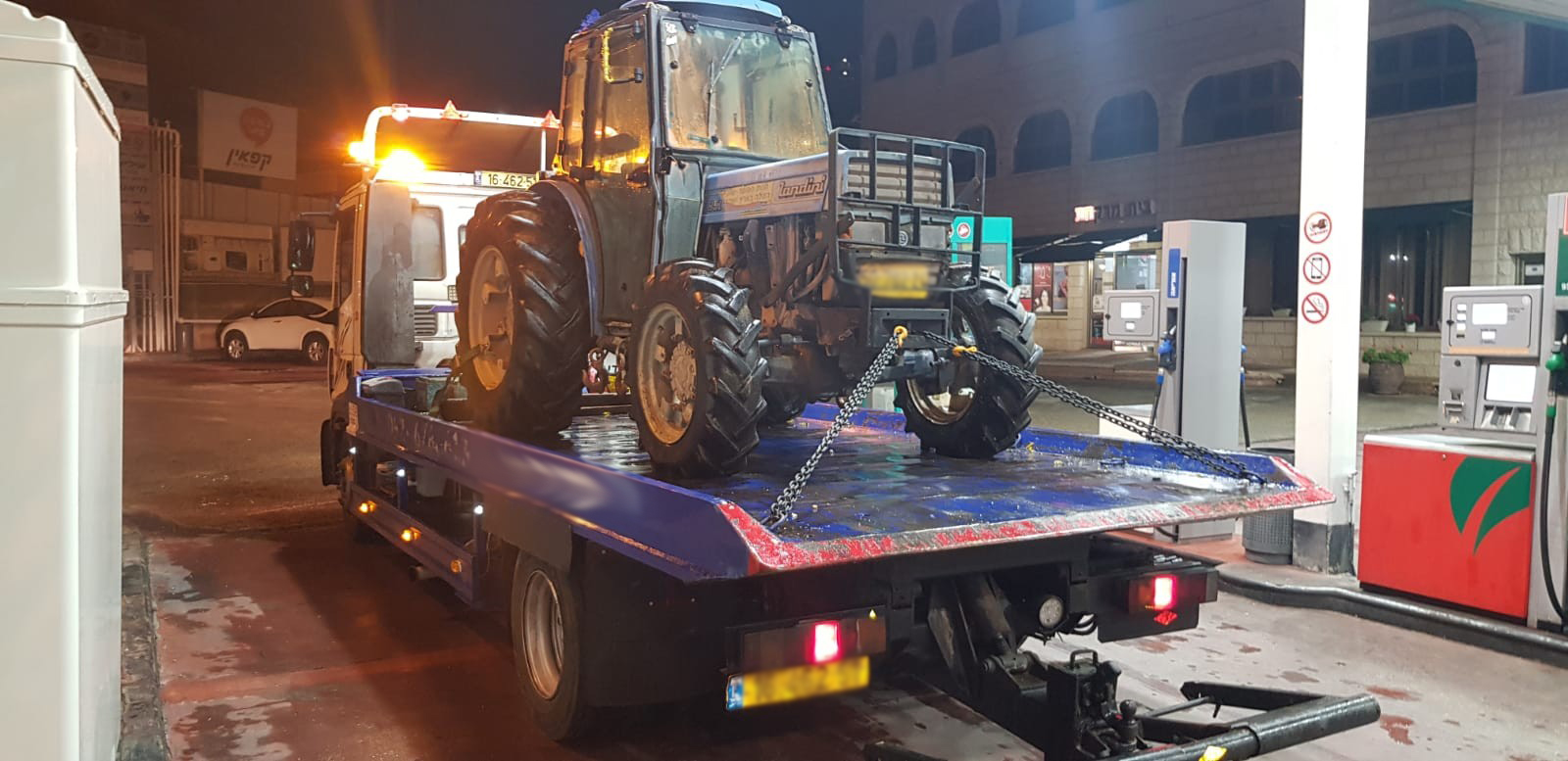 טרקטור מועמס על משאית גרר בלילה