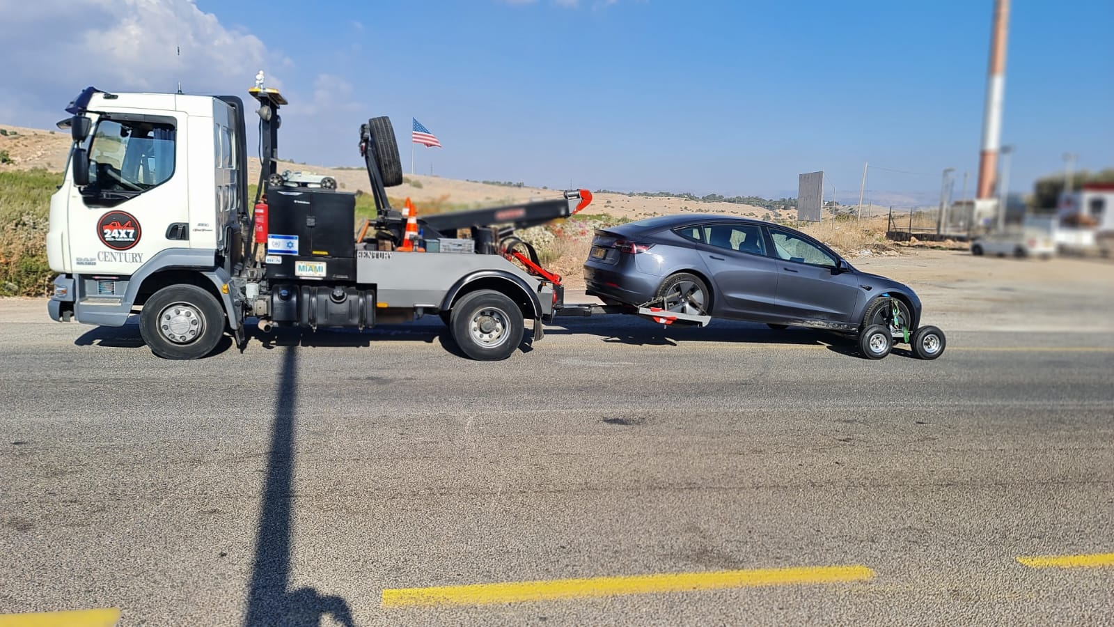 משאית גרר גוררת מכונית אפורה בכביש